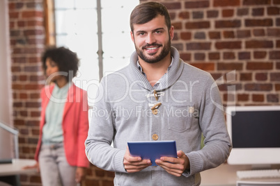 Man using digital tablet with colleague behind in office