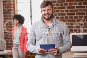 Man using digital tablet with colleague behind in office