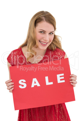Smiling blonde showing a red sale poster