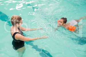 Cute little girl learning to swim with coach