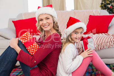 Festive mother and daughter smiling at camera with gifts