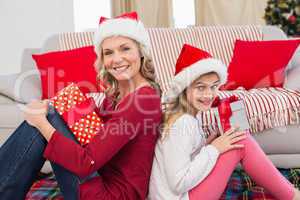 Festive mother and daughter smiling at camera with gifts