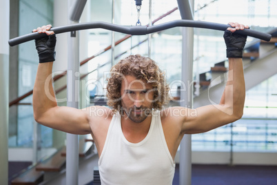 Handsome man exercising on a lat machine in gym