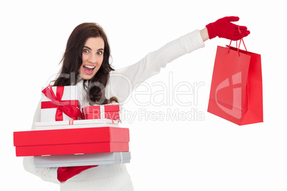 Excited brunette holding gifts and showing shopping bag