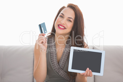 Pretty brunette showing credit card and screen of laptop