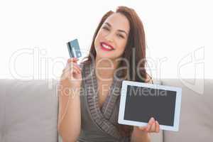 Pretty brunette showing credit card and screen of laptop