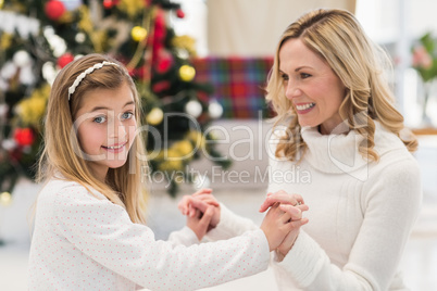 Festive mother and daughter beside christmas tree