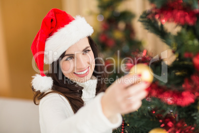Happy brunette decorating a christmas tree