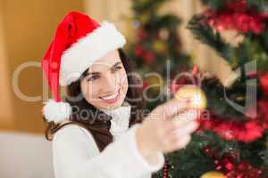 Happy brunette decorating a christmas tree