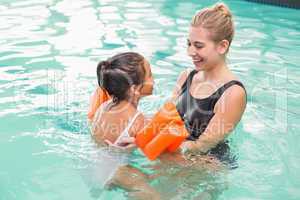 Cute little girl learning to swim with coach