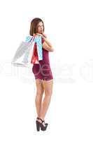Pretty woman holding shopping bags with finger to her lips