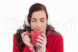 Woman in winter clothes enjoying a hot drink eyes closed