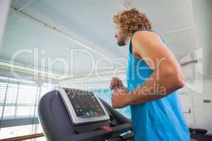 Side view of man running on treadmill in gym