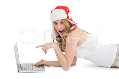 Woman lying on the floor while pointing to laptop