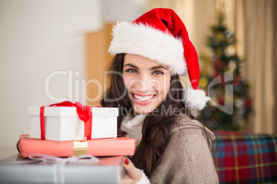 Festive brunette holding pile of gifts at christmas