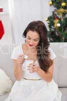 Brunette holding mug with marshmallow at christmas