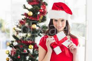 Festive brunette holding gift at christmas