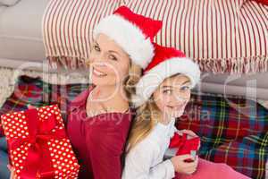 Festive mother and daughter smiling at camera with gifts