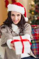 Festive brunette showing gift at christmas