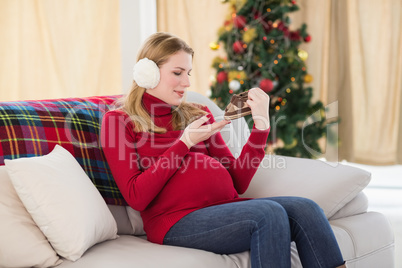 Pregnant woman looking at baby shoes sitting on sofa