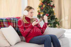 Pregnant woman looking at baby shoes sitting on sofa