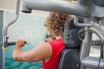 Side view of man working on fitness machine at gym