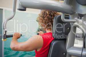 Side view of man working on fitness machine at gym