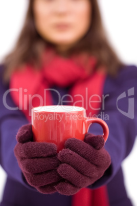 Woman in winter clothes offering a mug