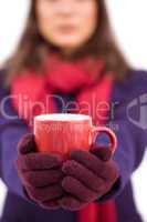Woman in winter clothes offering a mug