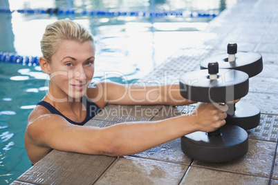 Female swimmer with foam dumbbells in swimming pool