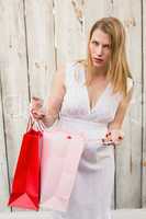 Blonde woman opening a gift bag while looking at camera