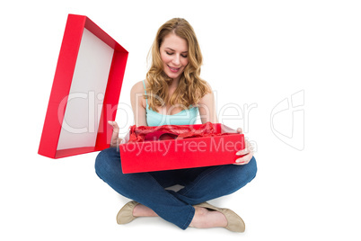 Pretty woman opening a gift smiling at it