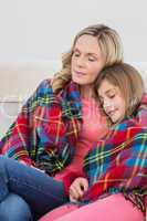 Festive mother and daughter wrapped in blanket