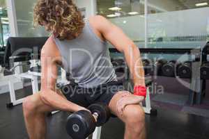 Young man exercising with dumbbell in gym