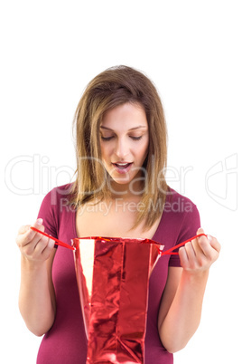 Astonished brunette opening a gift bag