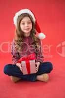 Happy little girl in santa hat holding gift