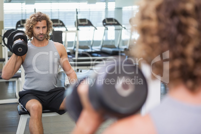 Young man exercising with dumbbell in gym