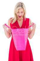 Stylish blonde in red dress opening gift bag