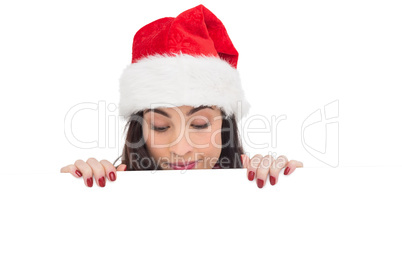 Pretty brunette in santa hat showing white poster