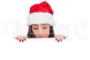 Pretty brunette in santa hat showing white poster