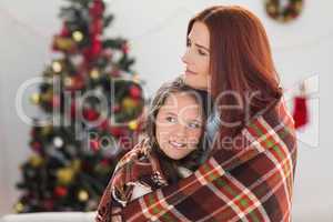 Festive mother and daughter wrapped in blanket