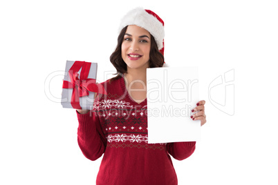 Festive brunette holding gift and showing paper