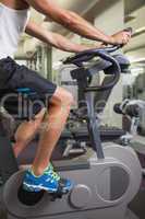 Cropped man working out on exercise bike at gym