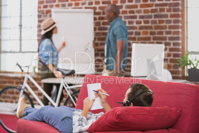 Relaxed casual man lying and writing note on couch