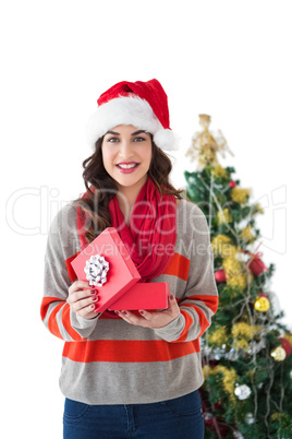 Festive brunette opening gift by the tree