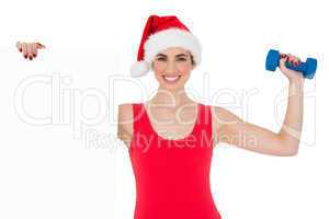 Festive fit brunette holding page and dumbbell