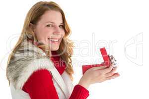 Surprised woman opening gift while looking at camera