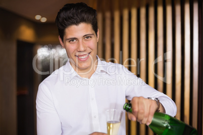Handsome man smiling at camera pouring champagne