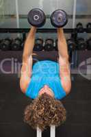 Young man exercising with dumbbells in gym