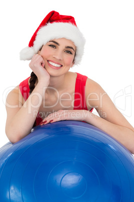 Festive fit brunette leaning on exercise ball